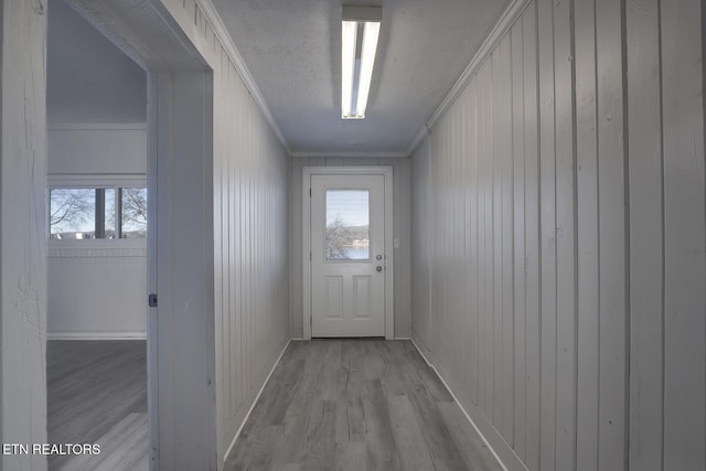 doorway to outside with a textured ceiling, light hardwood / wood-style flooring, crown molding, and a wealth of natural light