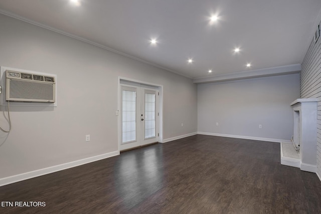 unfurnished living room featuring a wall unit AC, crown molding, dark wood-type flooring, french doors, and a fireplace