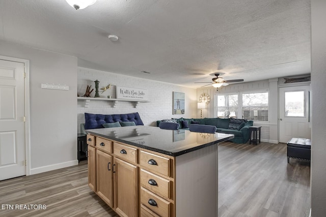 kitchen with a kitchen island, a textured ceiling, ceiling fan, and wood-type flooring