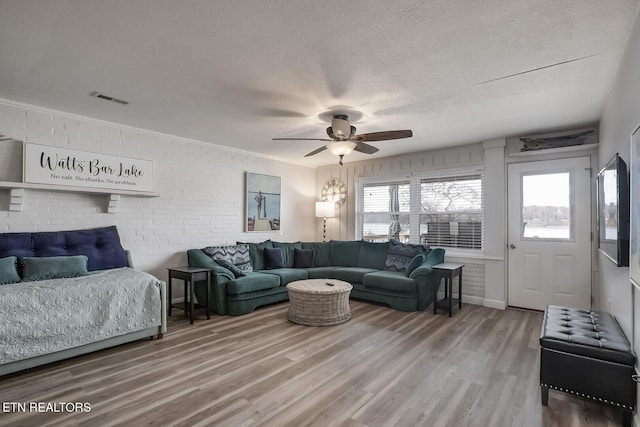 living room with brick wall, a textured ceiling, ceiling fan, and wood-type flooring