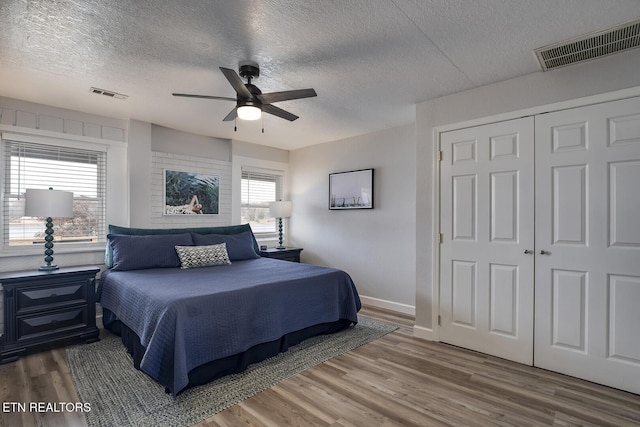 bedroom with a closet, a textured ceiling, ceiling fan, and wood-type flooring