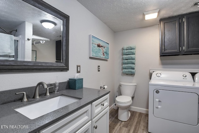 bathroom with washer / clothes dryer, a textured ceiling, hardwood / wood-style flooring, toilet, and vanity