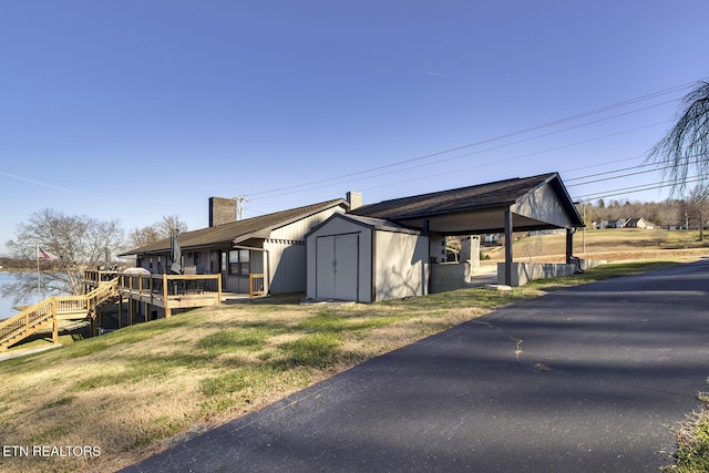 view of side of home with a wooden deck, a lawn, and a storage shed