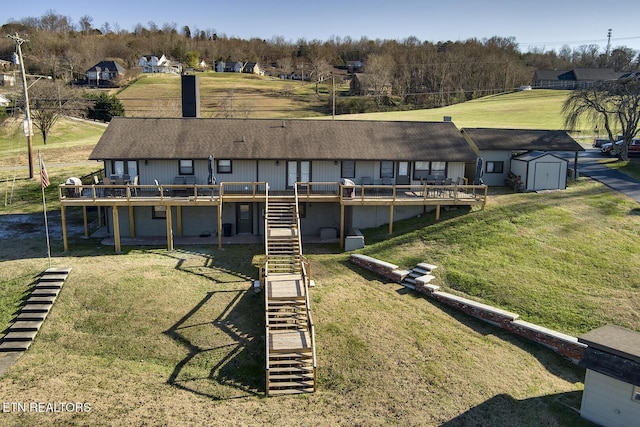 rear view of property with a wooden deck, a storage unit, and a lawn