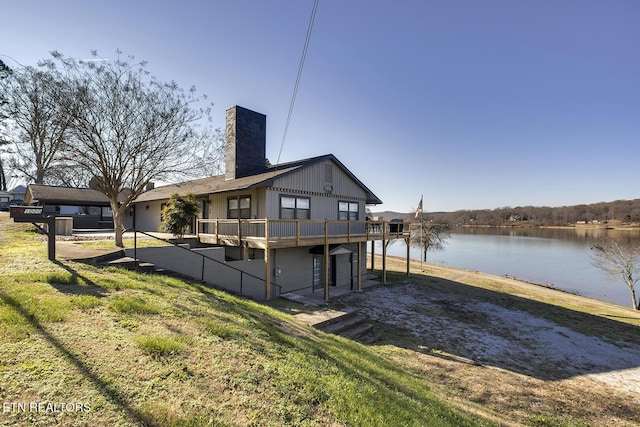 rear view of house with a yard and a deck with water view