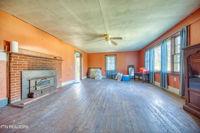 unfurnished living room featuring hardwood / wood-style floors, ceiling fan, and a brick fireplace