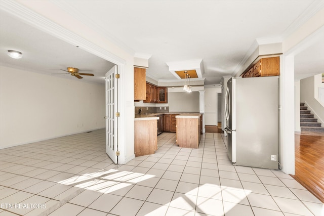 kitchen with ornamental molding, stainless steel fridge, a center island, and light tile patterned floors