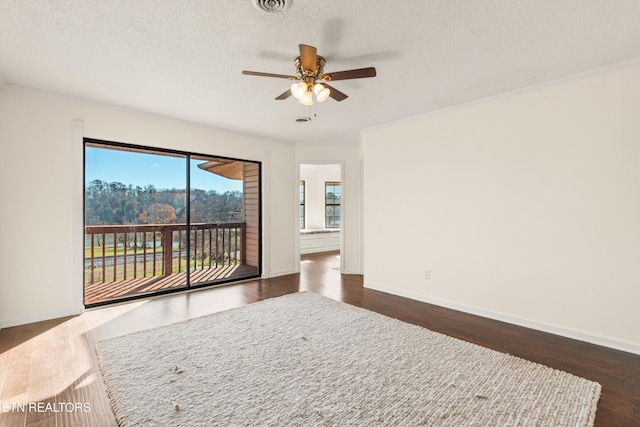 empty room with dark wood-type flooring, a textured ceiling, ceiling fan, and crown molding