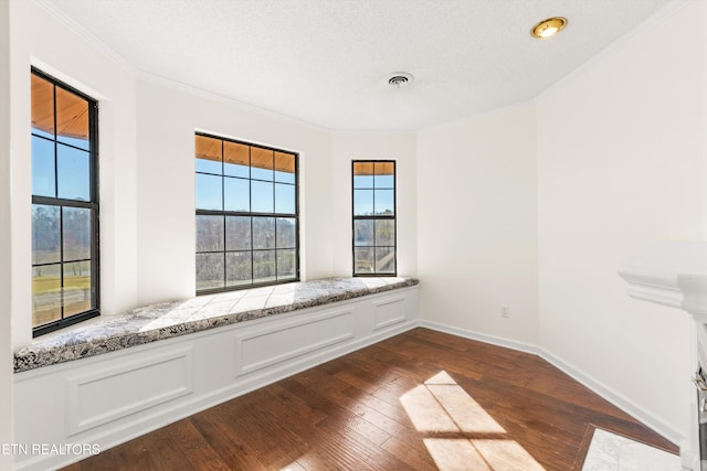 empty room featuring a textured ceiling, dark wood-type flooring, and ornamental molding