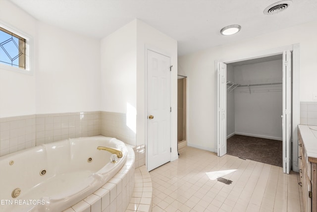 bathroom with tile patterned flooring and a relaxing tiled tub