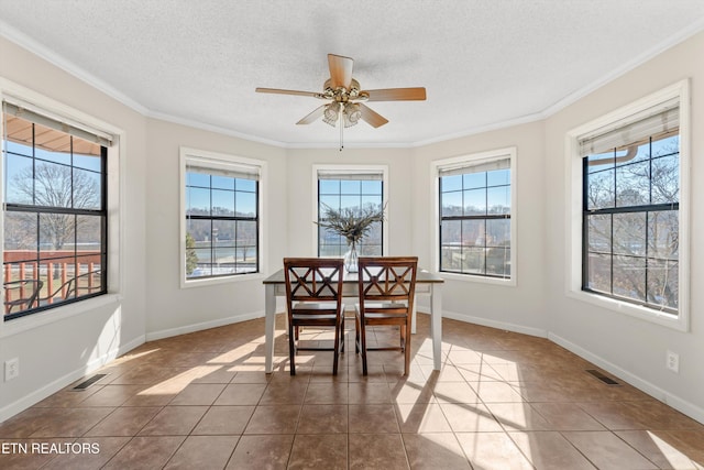 tiled dining room with a textured ceiling, ceiling fan, and crown molding