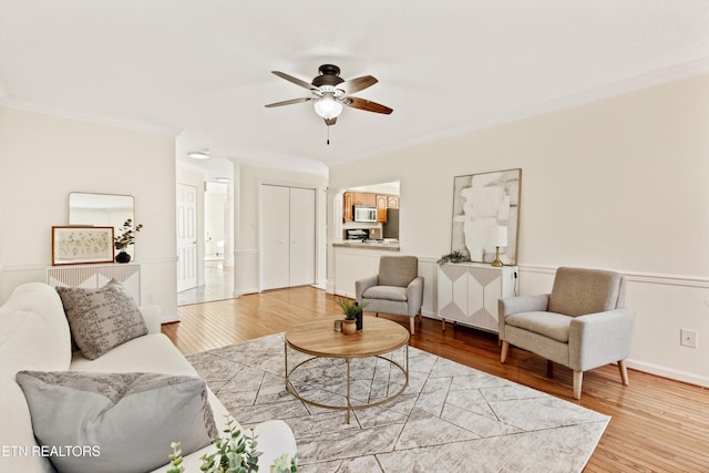 living room featuring ceiling fan, crown molding, and wood-type flooring