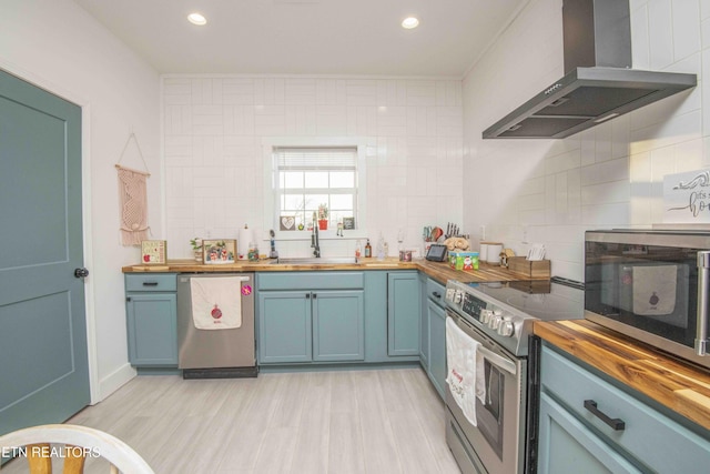 kitchen with wood counters, stainless steel appliances, extractor fan, sink, and light hardwood / wood-style floors