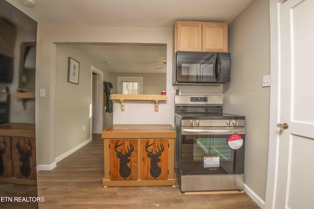 kitchen featuring ceiling fan, stainless steel range, light brown cabinets, and hardwood / wood-style flooring