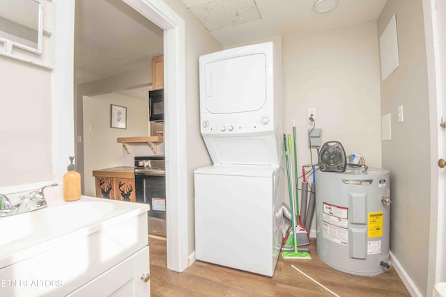 clothes washing area featuring electric water heater, light hardwood / wood-style flooring, stacked washer / drying machine, and sink