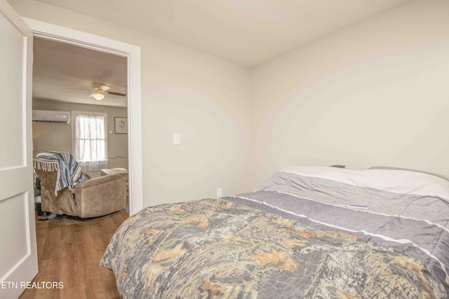 bedroom with hardwood / wood-style floors, a wall mounted AC, and ceiling fan