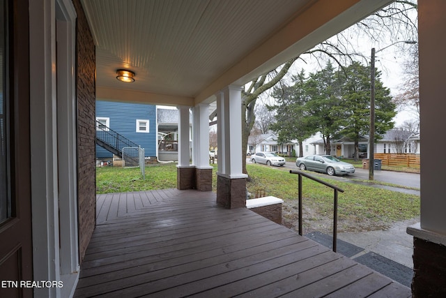 wooden deck featuring covered porch and a lawn