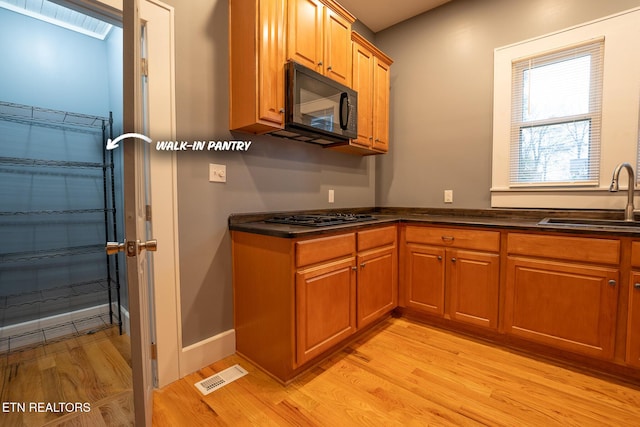 kitchen featuring sink, light hardwood / wood-style flooring, and black appliances