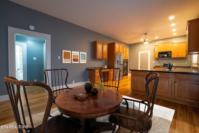 dining space with sink, light hardwood / wood-style flooring, and ceiling fan