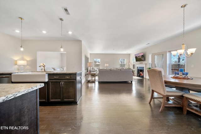 kitchen featuring decorative light fixtures, dark hardwood / wood-style floors, sink, dark brown cabinetry, and light stone countertops