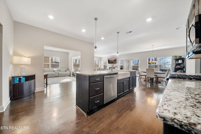 kitchen with pendant lighting, appliances with stainless steel finishes, dark wood-type flooring, an island with sink, and sink