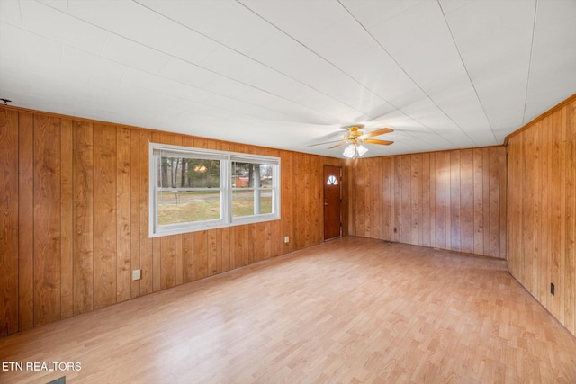 spare room with ceiling fan, wooden walls, and light hardwood / wood-style flooring