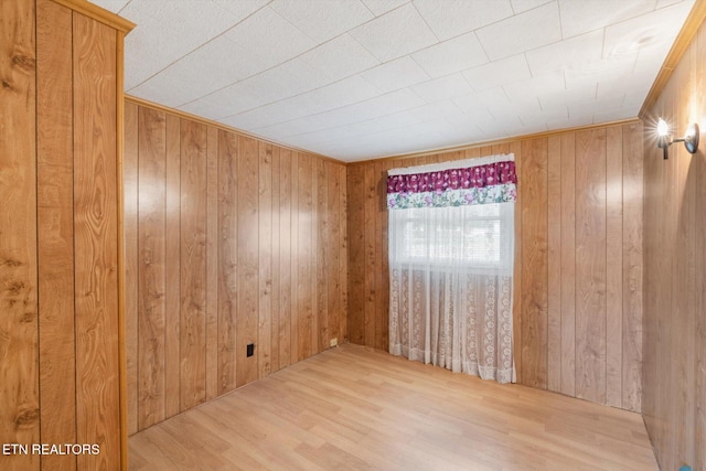 empty room with light wood-type flooring and wooden walls