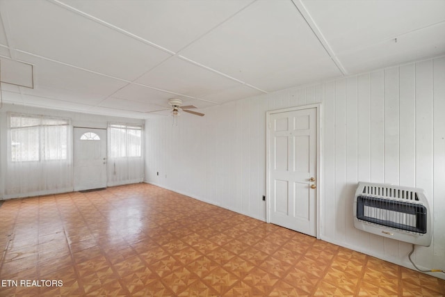 spare room with heating unit, wooden walls, light parquet floors, and ceiling fan