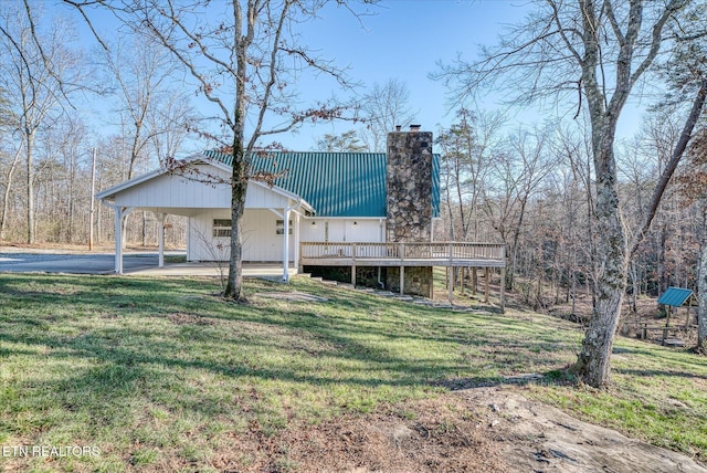 rear view of house featuring a yard, a carport, and a wooden deck