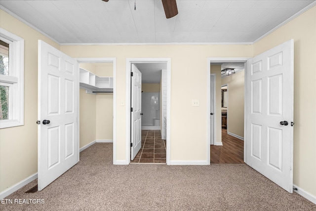 unfurnished bedroom featuring ceiling fan, a closet, dark carpet, and ornamental molding