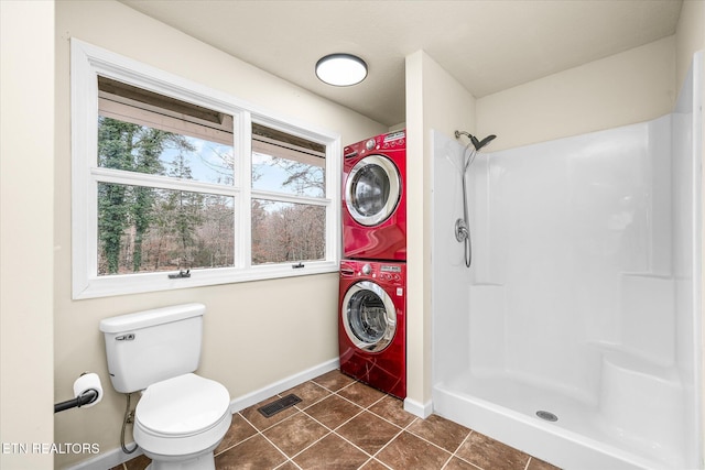 bathroom featuring tile patterned floors, toilet, stacked washer / dryer, and walk in shower