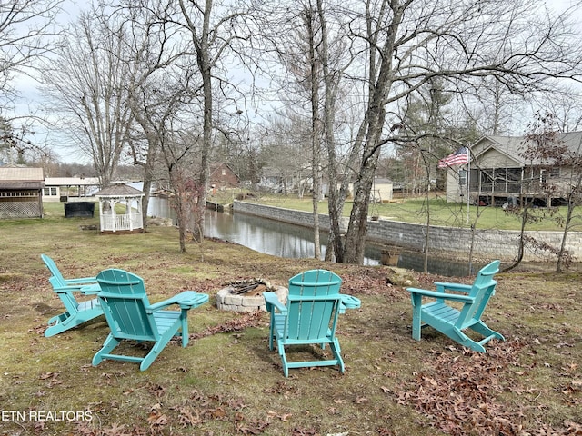 view of yard featuring a water view, an outdoor structure, and an outdoor fire pit