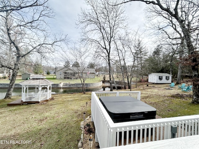 view of yard featuring a gazebo, a water view, a hot tub, and a storage unit