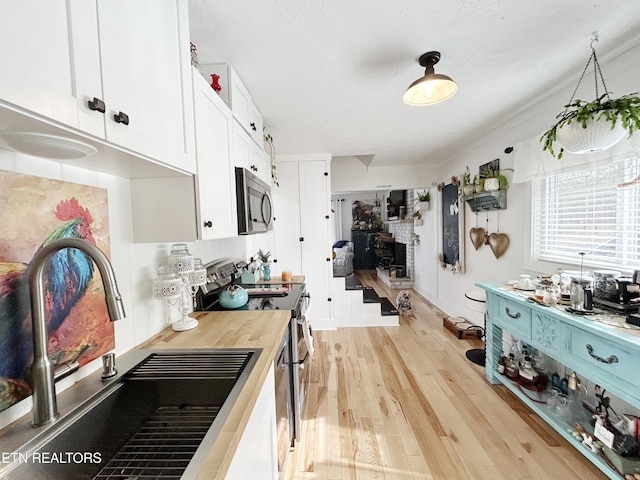 kitchen with white cabinets, sink, stainless steel appliances, and light hardwood / wood-style flooring