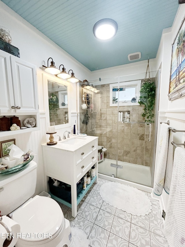 bathroom featuring tile patterned flooring, a shower with door, vanity, and toilet