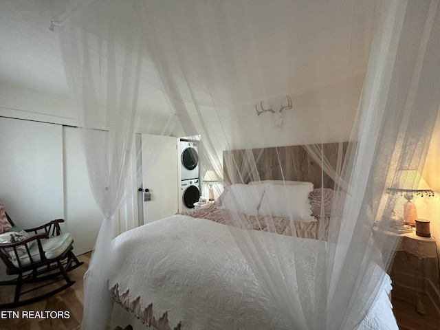 bedroom featuring hardwood / wood-style floors and stacked washer and dryer