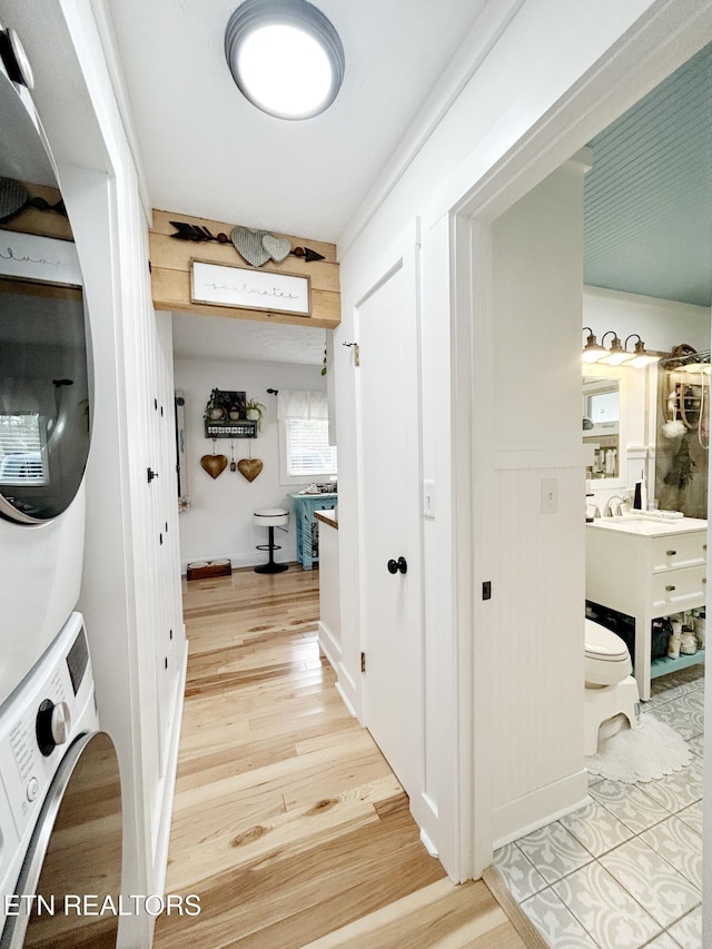 laundry area with hardwood / wood-style floors, stacked washer / drying machine, and sink