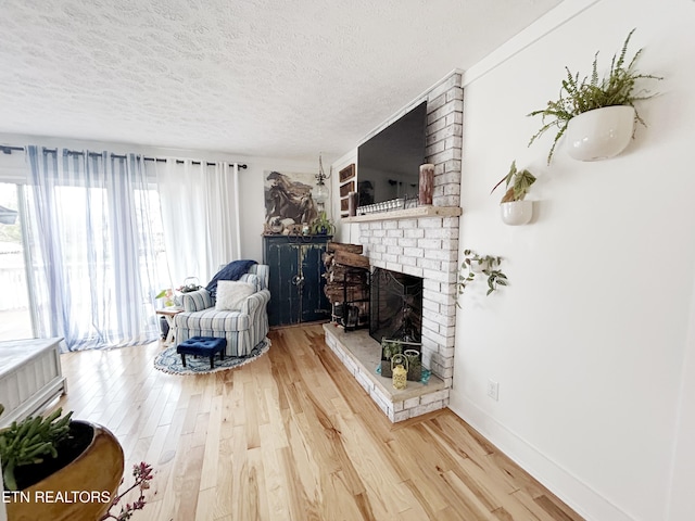 living room with hardwood / wood-style floors, a textured ceiling, and a brick fireplace