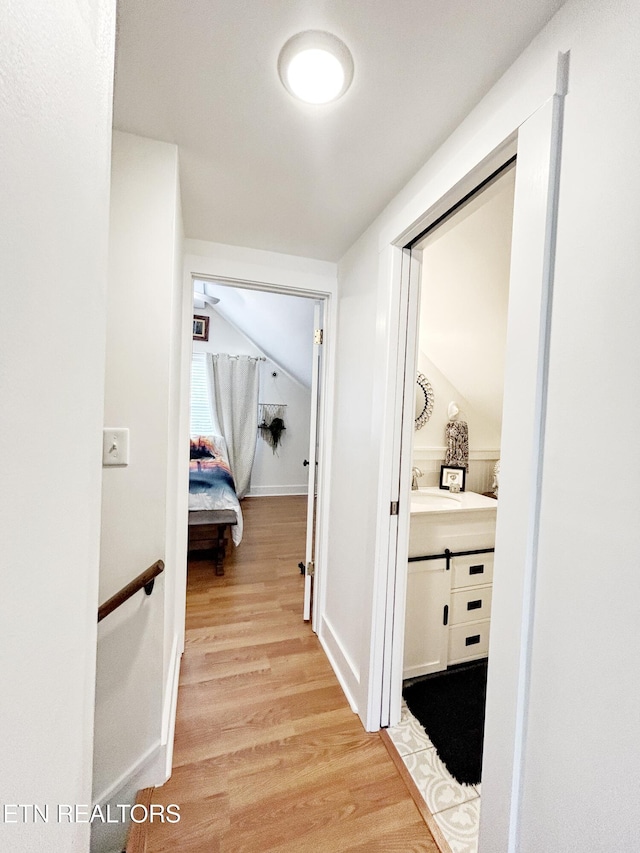 corridor featuring light hardwood / wood-style flooring and vaulted ceiling