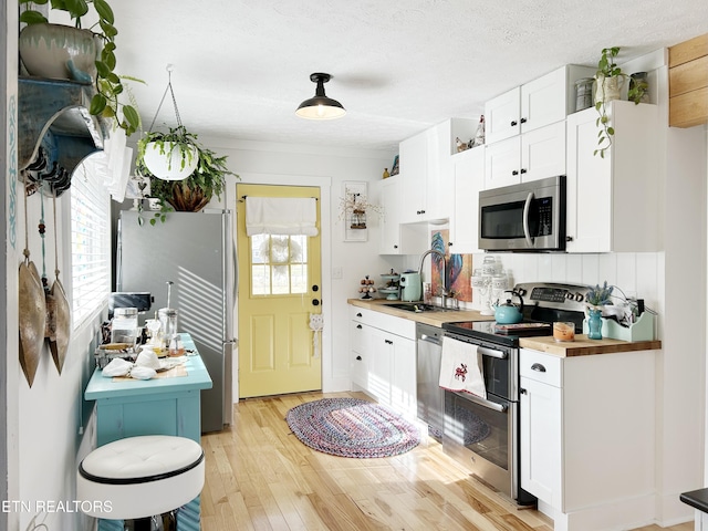 kitchen featuring wood counters, stainless steel appliances, and white cabinets