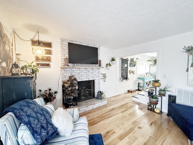 living room with hardwood / wood-style floors, a textured ceiling, and a brick fireplace