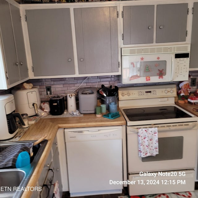 kitchen with gray cabinets, sink, white appliances, and backsplash