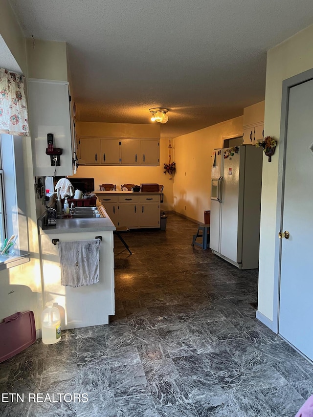 kitchen with white refrigerator with ice dispenser, a textured ceiling, kitchen peninsula, and sink