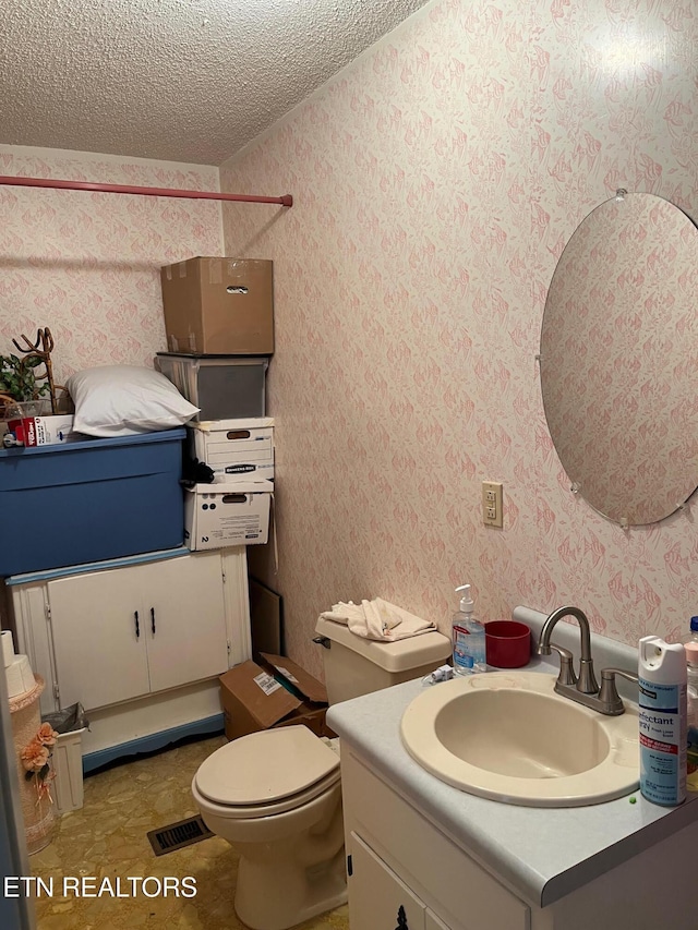 bathroom featuring vanity, a textured ceiling, and toilet