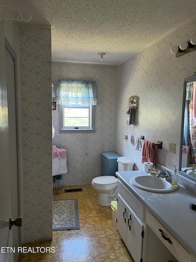 bathroom with vanity, toilet, and a textured ceiling