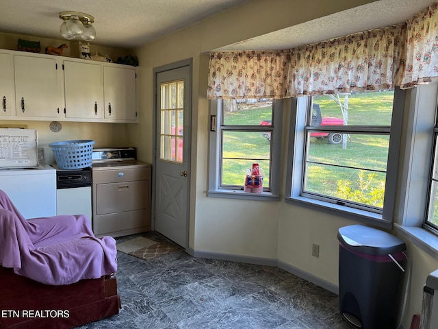 kitchen featuring plenty of natural light, white cabinets, washer and dryer, and a textured ceiling