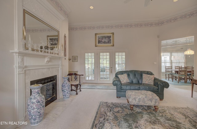 living room featuring ceiling fan, a healthy amount of sunlight, light carpet, and a high end fireplace