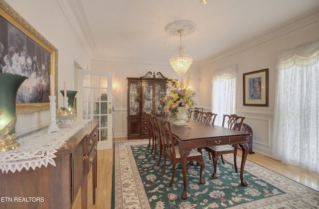 dining space with hardwood / wood-style floors, a notable chandelier, and ornamental molding