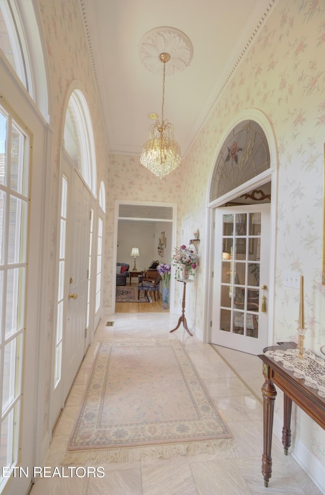 entryway with a notable chandelier and ornamental molding