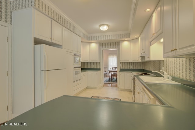 kitchen with white cabinetry, crown molding, white appliances, and sink